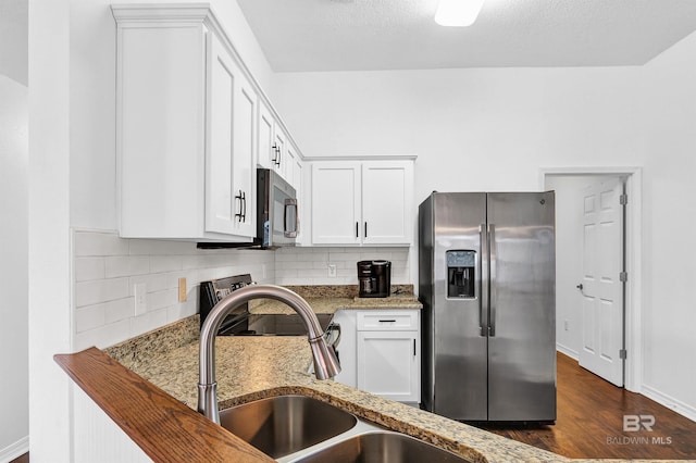 kitchen featuring white cabinets, tasteful backsplash, light stone countertops, and stainless steel appliances