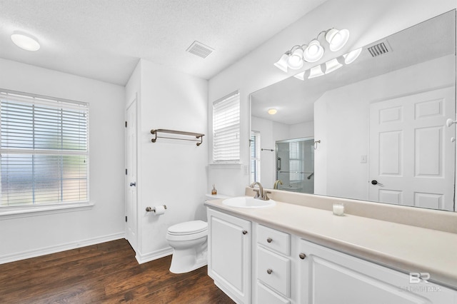 full bathroom featuring toilet, wood finished floors, visible vents, and a stall shower