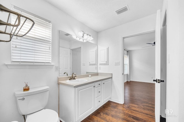 bathroom featuring toilet, baseboards, visible vents, wood finished floors, and vanity