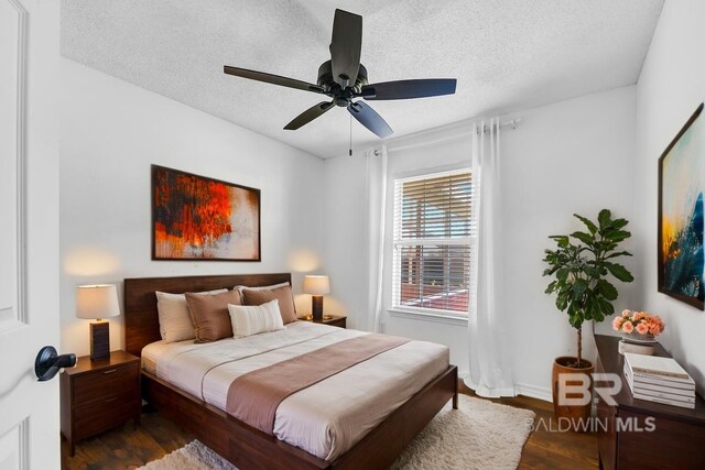 bedroom with a ceiling fan, baseboards, a textured ceiling, and dark wood-style flooring