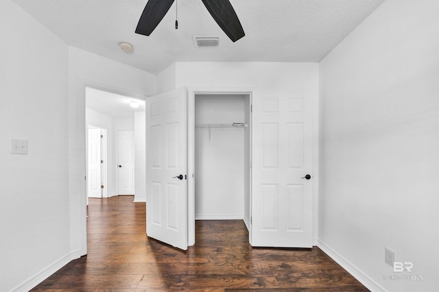 unfurnished bedroom featuring baseboards, dark wood-type flooring, visible vents, and a closet