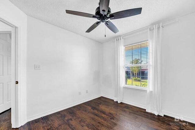 spare room with dark wood finished floors, a textured ceiling, a ceiling fan, and baseboards