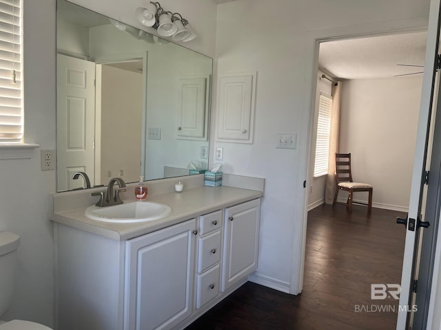 bathroom featuring toilet, vanity, wood finished floors, and baseboards