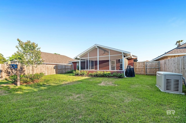 rear view of property with a fenced backyard, a sunroom, a yard, and a ceiling fan