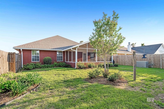 view of front of property featuring brick siding, a front lawn, a sunroom, and a fenced backyard