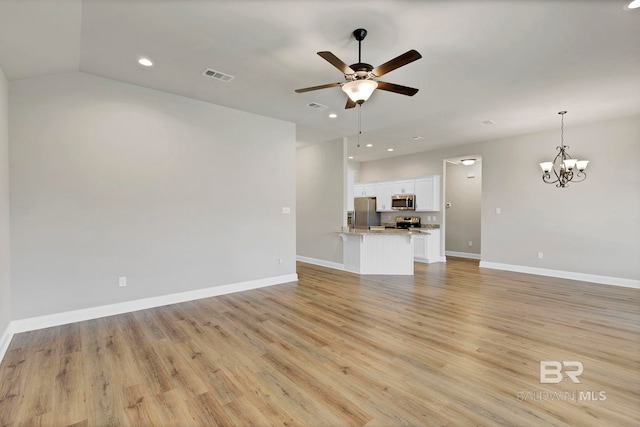 unfurnished living room with ceiling fan with notable chandelier, baseboards, visible vents, and light wood-style floors