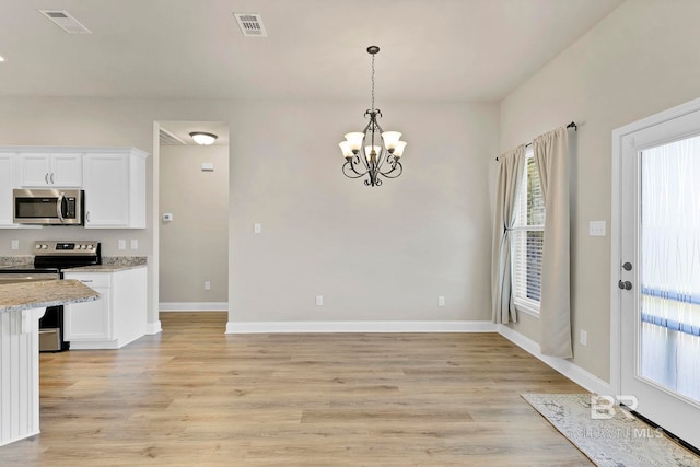 unfurnished dining area with light wood-style flooring, a notable chandelier, baseboards, and visible vents
