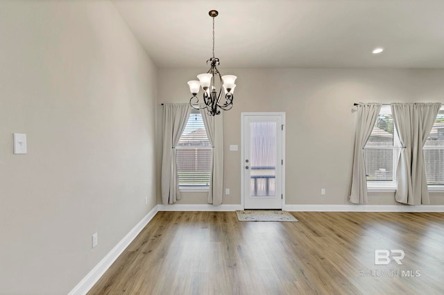 foyer entrance featuring a wealth of natural light, a chandelier, wood finished floors, and baseboards