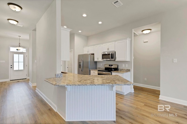 kitchen with stainless steel appliances, visible vents, a kitchen bar, white cabinets, and light wood-style floors