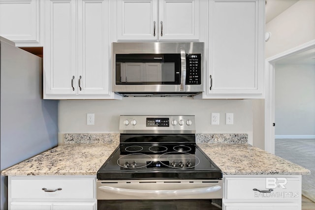 kitchen with light stone countertops, stainless steel appliances, white cabinetry, and carpet