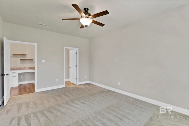 unfurnished bedroom featuring light colored carpet, visible vents, a ceiling fan, connected bathroom, and baseboards