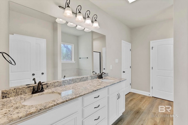 bathroom featuring baseboards, double vanity, a sink, and wood finished floors