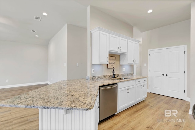 kitchen with a sink, white cabinets, stainless steel dishwasher, visible vents, and light wood-style floors