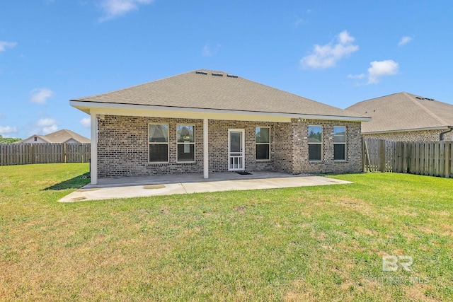 rear view of property with a yard, a patio area, brick siding, and a fenced backyard