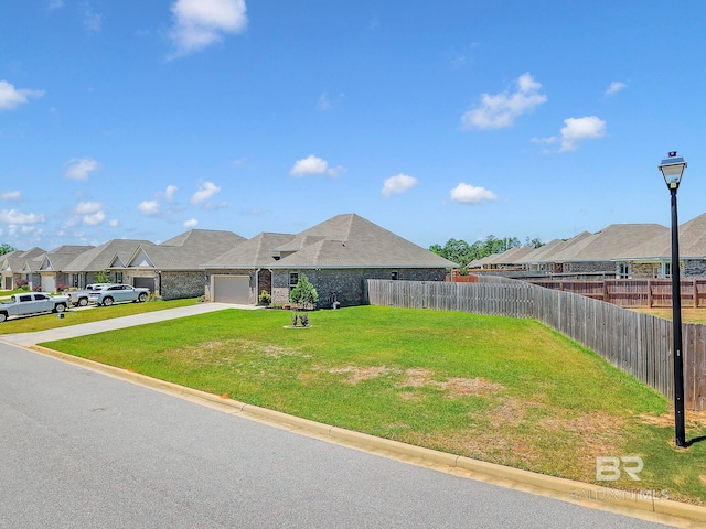 view of yard with an attached garage, fence, driveway, and a residential view