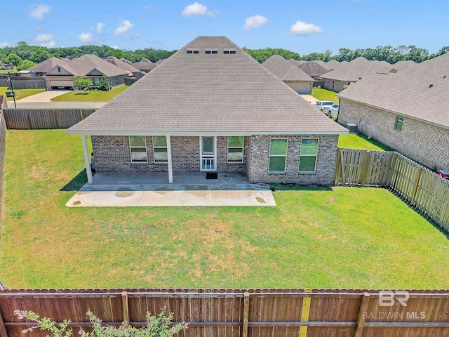 rear view of property featuring a patio, a shingled roof, a fenced backyard, a yard, and brick siding