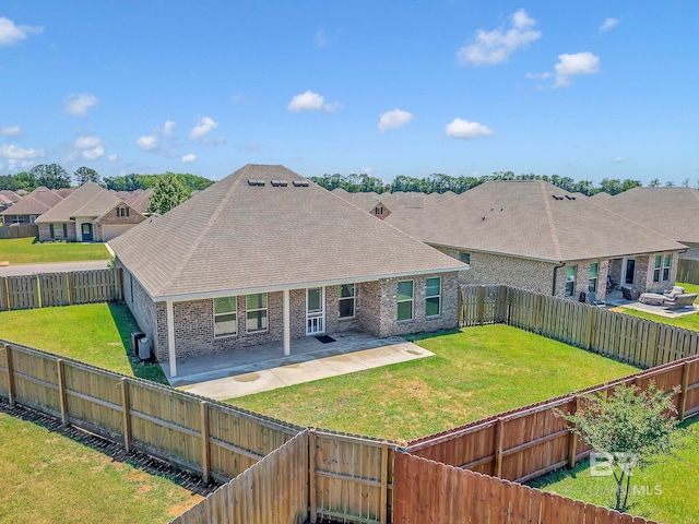 rear view of house featuring a patio, a lawn, a shingled roof, a fenced backyard, and brick siding