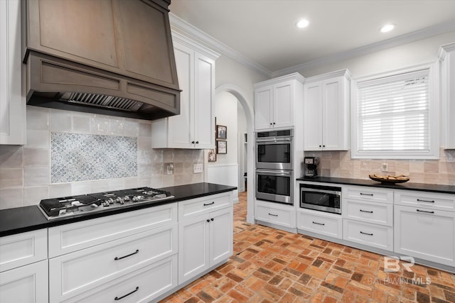 kitchen featuring white cabinetry, decorative backsplash, ornamental molding, and stainless steel appliances