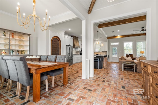 dining area with sink, beam ceiling, ornamental molding, and a chandelier