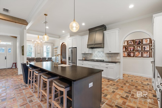 kitchen with custom exhaust hood, an island with sink, appliances with stainless steel finishes, and sink