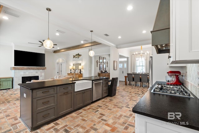 kitchen featuring sink, a tile fireplace, premium range hood, appliances with stainless steel finishes, and hanging light fixtures