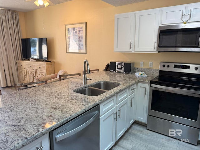 kitchen with light stone countertops, sink, a textured ceiling, white cabinetry, and stainless steel appliances