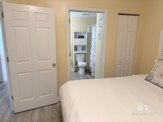 bedroom with ensuite bathroom and light hardwood / wood-style floors