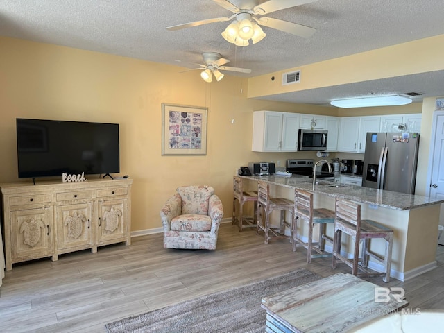 kitchen with a kitchen breakfast bar, kitchen peninsula, white cabinetry, and stainless steel appliances