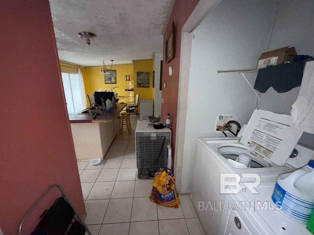 laundry area with laundry area, washer / dryer, a textured ceiling, a sink, and light tile patterned flooring