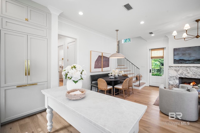 dining room featuring light hardwood / wood-style floors, ornamental molding, and a high end fireplace