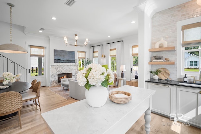 dining space with light wood-type flooring, ornamental molding, and a high end fireplace