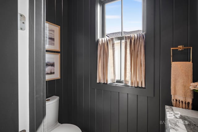 bathroom featuring wooden walls and toilet