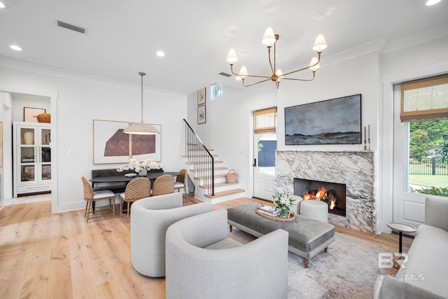 living room with light wood-type flooring, ornamental molding, a high end fireplace, and plenty of natural light