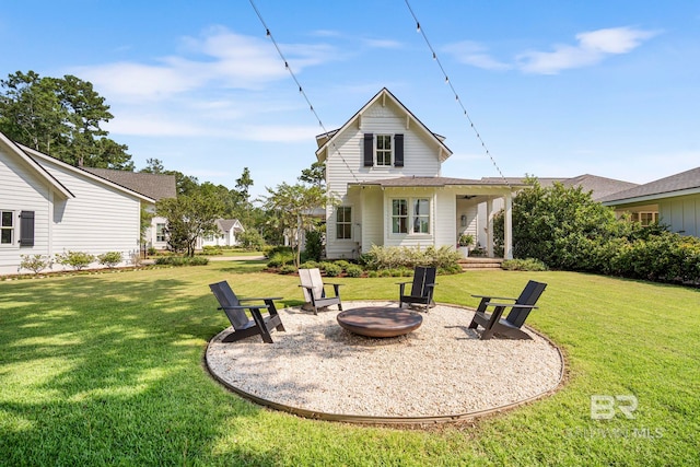 rear view of house with a lawn and a fire pit