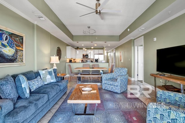 living room with tile patterned floors, ceiling fan, a tray ceiling, and ornamental molding