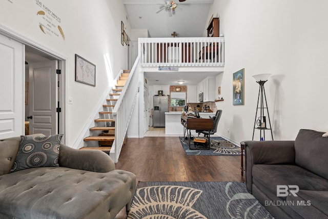 living room with a towering ceiling, hardwood / wood-style floors, and ceiling fan