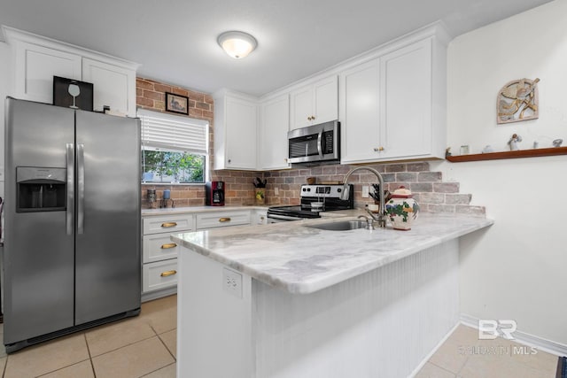 kitchen featuring light tile patterned flooring, white cabinetry, kitchen peninsula, decorative backsplash, and appliances with stainless steel finishes