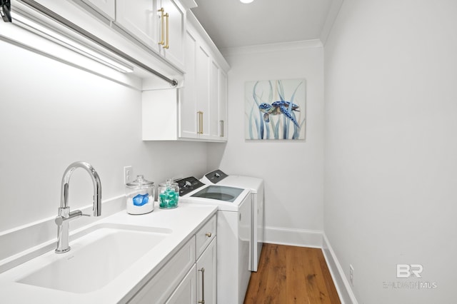 902 Inlet Cir, Gulf Shores, AL 36542 - clothes washing area with wood finished floors, cabinet space, ornamental molding, a sink, and washing machine and dryer