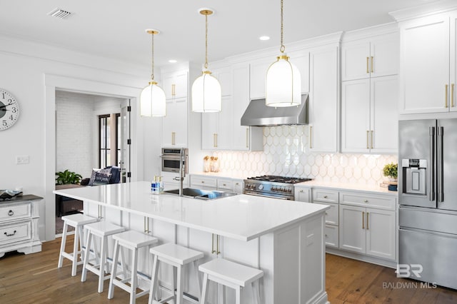 902 Inlet Cir, Gulf Shores, AL 36542 - kitchen with a breakfast bar, an island with sink, under cabinet range hood, backsplash, and appliances with stainless steel finishes