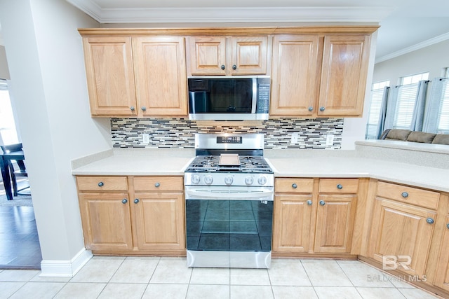 kitchen with light tile patterned flooring, backsplash, appliances with stainless steel finishes, and ornamental molding