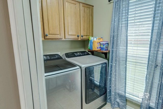 clothes washing area featuring washer and clothes dryer and cabinets