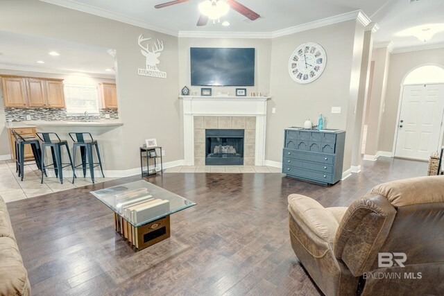 living room with a fireplace, ceiling fan, hardwood / wood-style floors, and crown molding