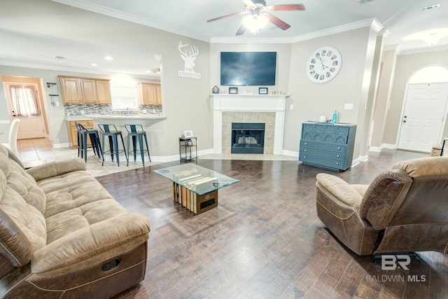 living room featuring hardwood / wood-style floors, a fireplace, ornamental molding, and ceiling fan