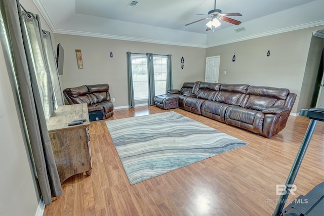 living room featuring light hardwood / wood-style floors, a raised ceiling, ornamental molding, and ceiling fan