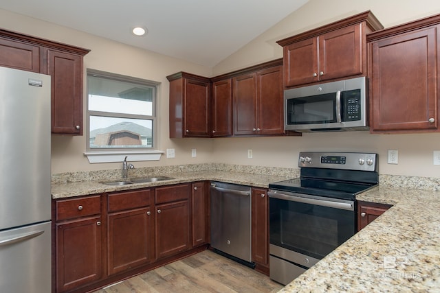 211 Lakefront Cir, Summerdale, AL 36580 - kitchen featuring stainless steel appliances, a sink, light wood-style floors, vaulted ceiling, and light stone countertops