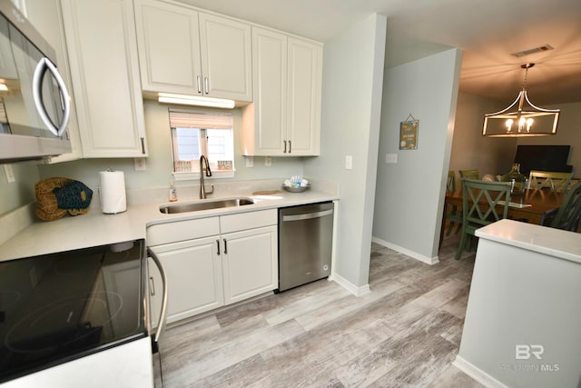 kitchen with hanging light fixtures, white cabinetry, an inviting chandelier, light wood-type flooring, and stainless steel appliances