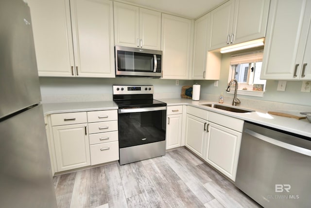 kitchen featuring light hardwood / wood-style floors, stainless steel appliances, white cabinetry, and sink