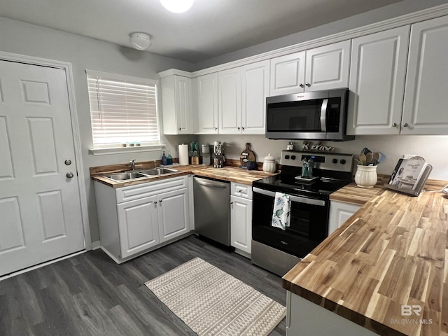 kitchen with butcher block countertops, a sink, appliances with stainless steel finishes, and white cabinets