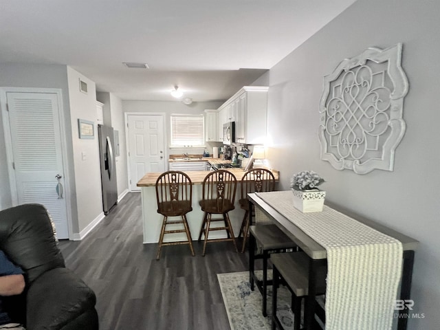 dining space featuring baseboards, visible vents, and dark wood finished floors