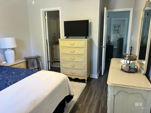 bedroom with dark wood-style floors, ensuite bath, and baseboards